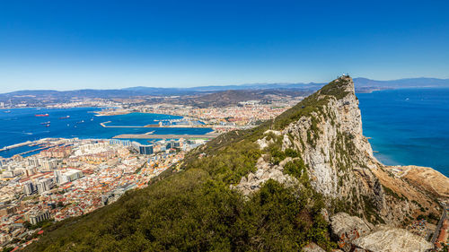 Scenic view of sea and mountains against clear blue sky