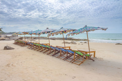 Deck chairs on beach against sky