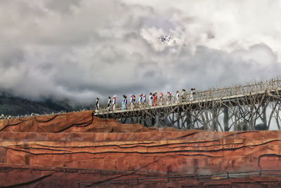 People on bridge against sky