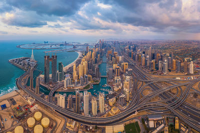 Cityscape and sea against cloudy sky