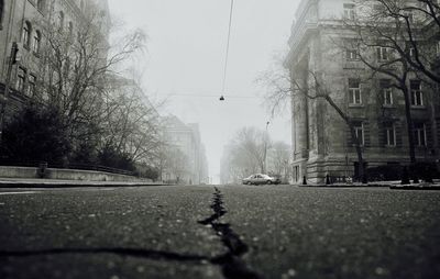 Wet street in city against clear sky