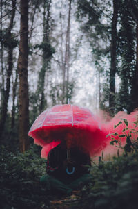 Man with umbrella and red smoke sitting in forest
