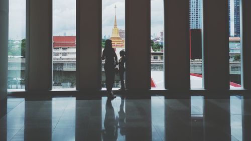 Silhouette people standing by window