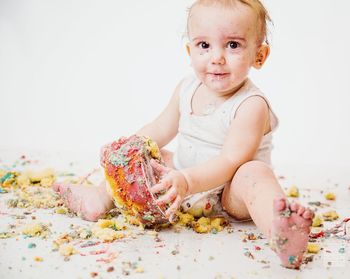 Cute toddler playing with cake over white background