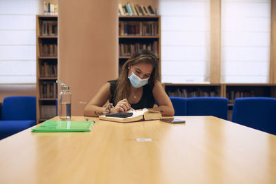 A girl with a mask studying in the university library