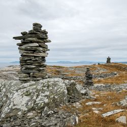 Stack of stones on rock against sky