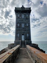 Lighthouse by sea against sky