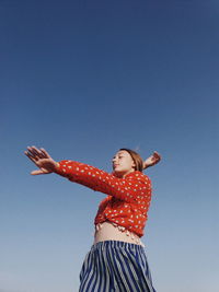 Low angle view of woman standing against blue sky