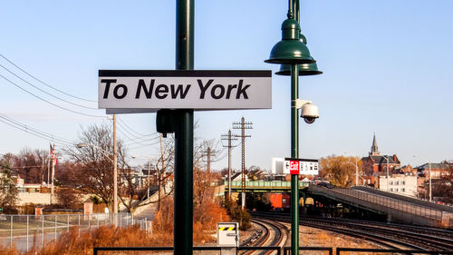 Information sign on railroad tracks against sky