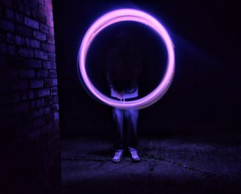 Man standing against illuminated lamp at night