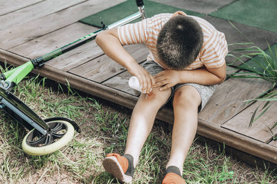 Child's leg injury. child injured his knee when he fell off scooter. boy uses antibacterial agent 