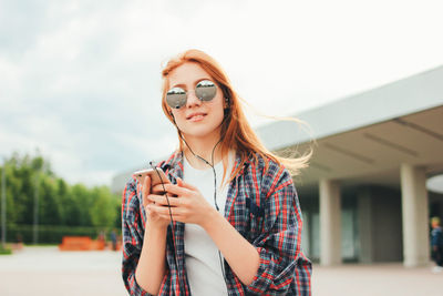 Young woman using mobile phone while standing outdoors