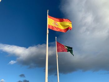 Low angle view of flags waving against sky