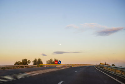 Cars on highway against sky during sunset