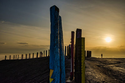 Wooden posts on beach against sky during sunset