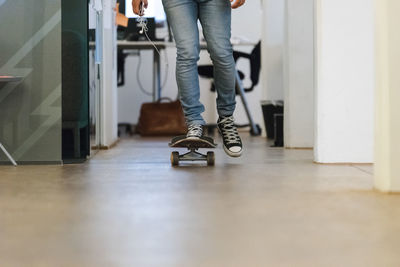 Low section of man skateboarding on floor