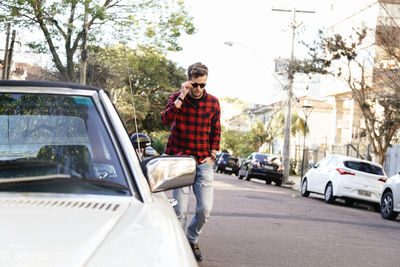 Man wearing plaid shirt and sunglasses while walking on road