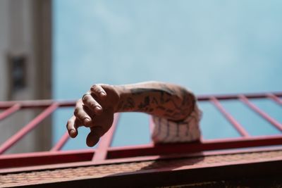 Cropped image of hand on railing against sky