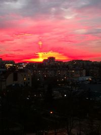 High angle view of illuminated buildings against romantic sky at sunset