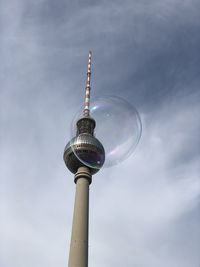 Low angle view of communications tower against cloudy sky