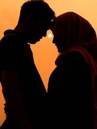 Side view of young couple against black background