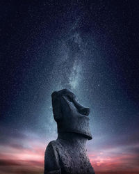 Low angle view of moai statue on mountain against starry sky at night