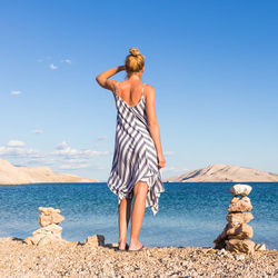 Rear view of man standing on beach against sky