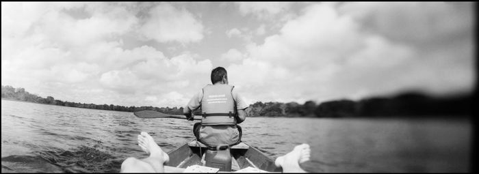 Woman sitting on boat in lake against sky