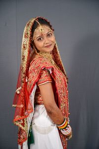 Portrait of smiling young bride standing against wall