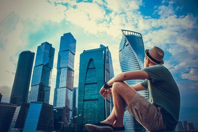 Low angle view of man sitting against sky