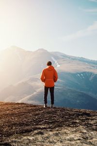 Rear view of man standing on mountain against sky