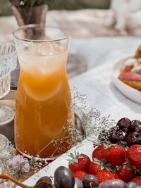 Close-up of an orange lemonade drink on a blanket with some berries in the right lower corner