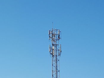 Low angle view of communications tower against clear blue sky