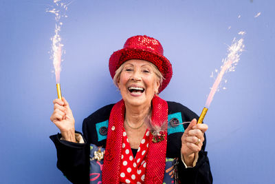 Portrait of smiling senior woman against yellow background