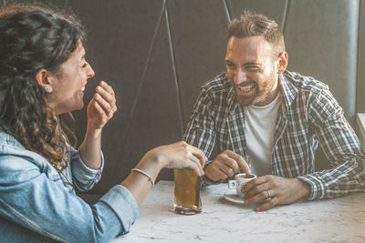 Couple laughing while sitting at cafe