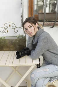 Portrait of teenage girl with camera on table