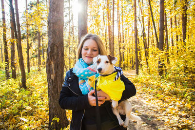 Happy woman with dog in forest