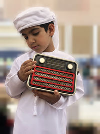 Boy holding vintage radio while standing at home
