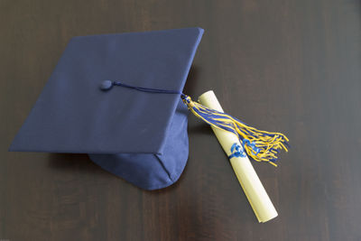 Close-up of mortarboard with certificate on table