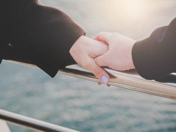 Cropped image of man holding hands of woman on railing