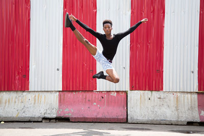 Full length of man jumping against corrugated iron