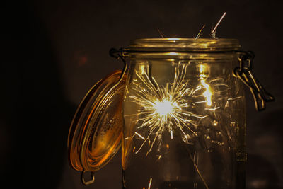 Close-up of sparkler in glass jar against black background