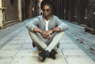 Young man sitting on footpath