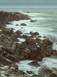 Scenic view of rocks on beach against sky