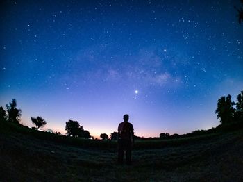 Silhouette people standing on field against sky at night