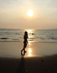 Silhouette man on beach against sky during sunset