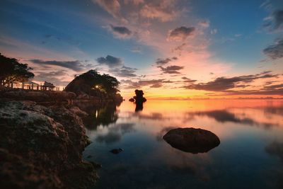 Silhouette rocks by sea against sky during sunset