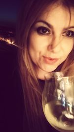 Close-up portrait of a smiling young woman drinking glass