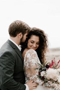 Young couple kissing against clear sky