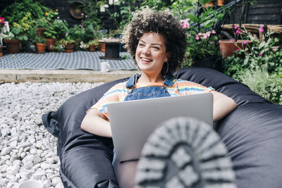 Smiling young woman using mobile phone while sitting outdoors